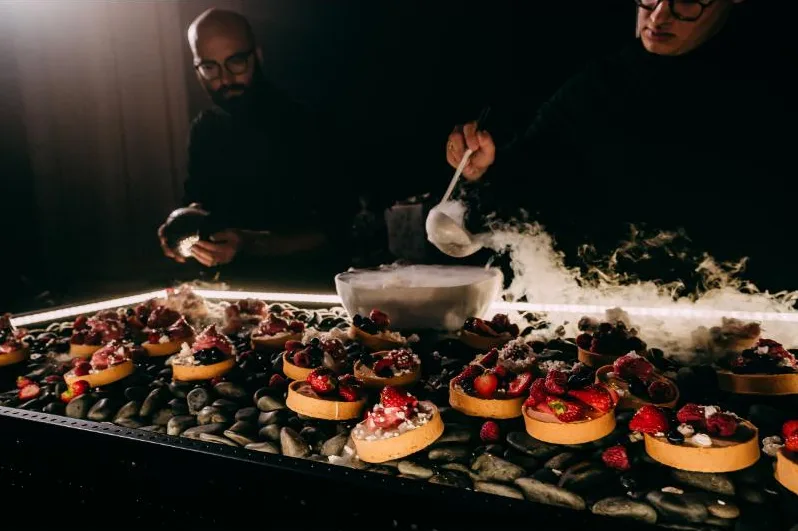Chefs pouring liquid nitrogen over berry tarts