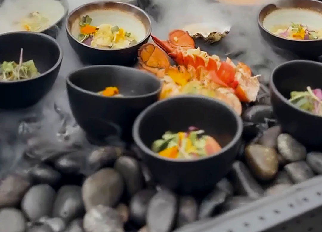 Lobster and seafood bowls on a stone table in a cloud of liquid-nitrogen fog