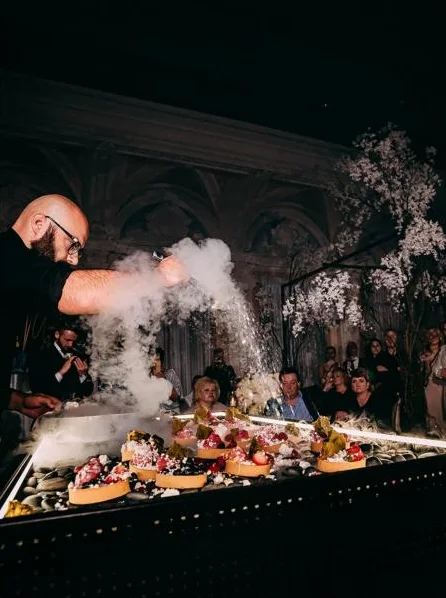 Chef pouring liquid nitrogen over the dessert table in front of guests